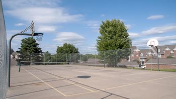 An outdoor basketball court with trees and houses in the background